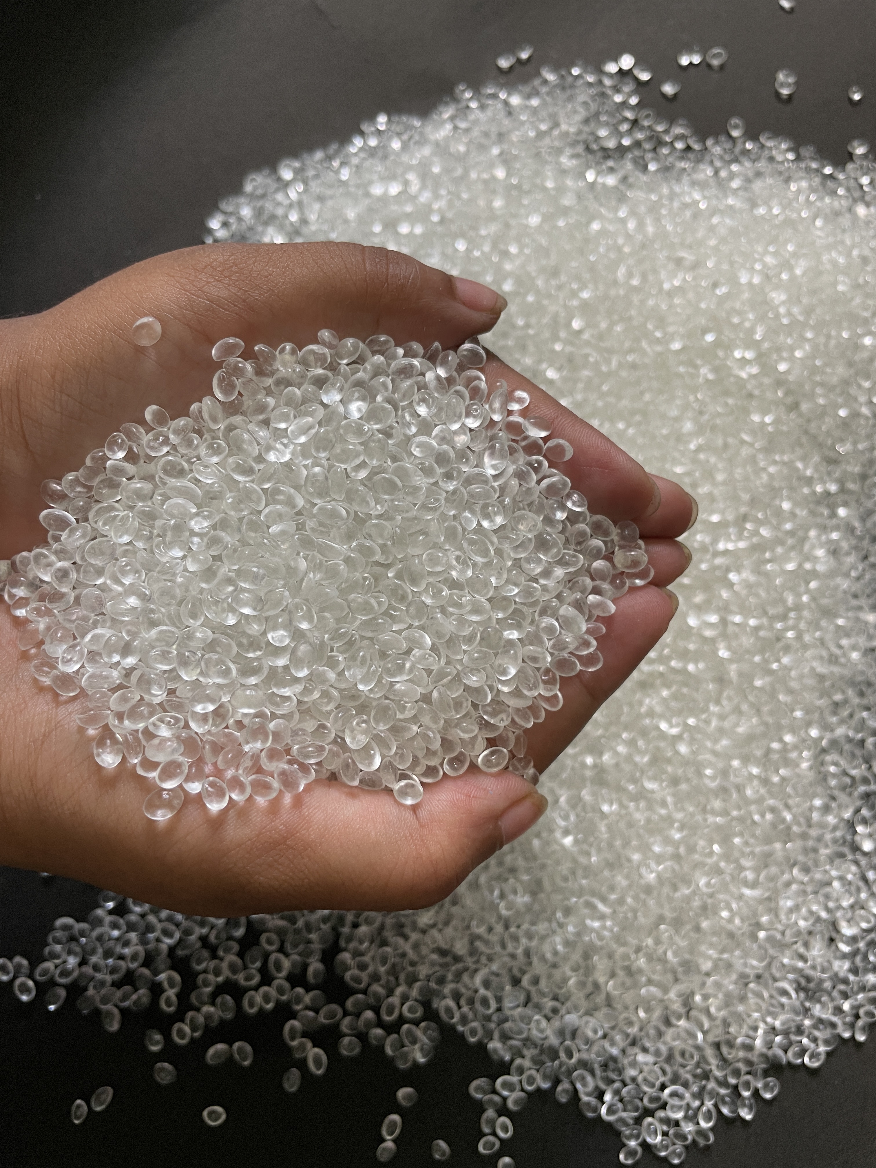 Hand holding transparent bioplastic granules