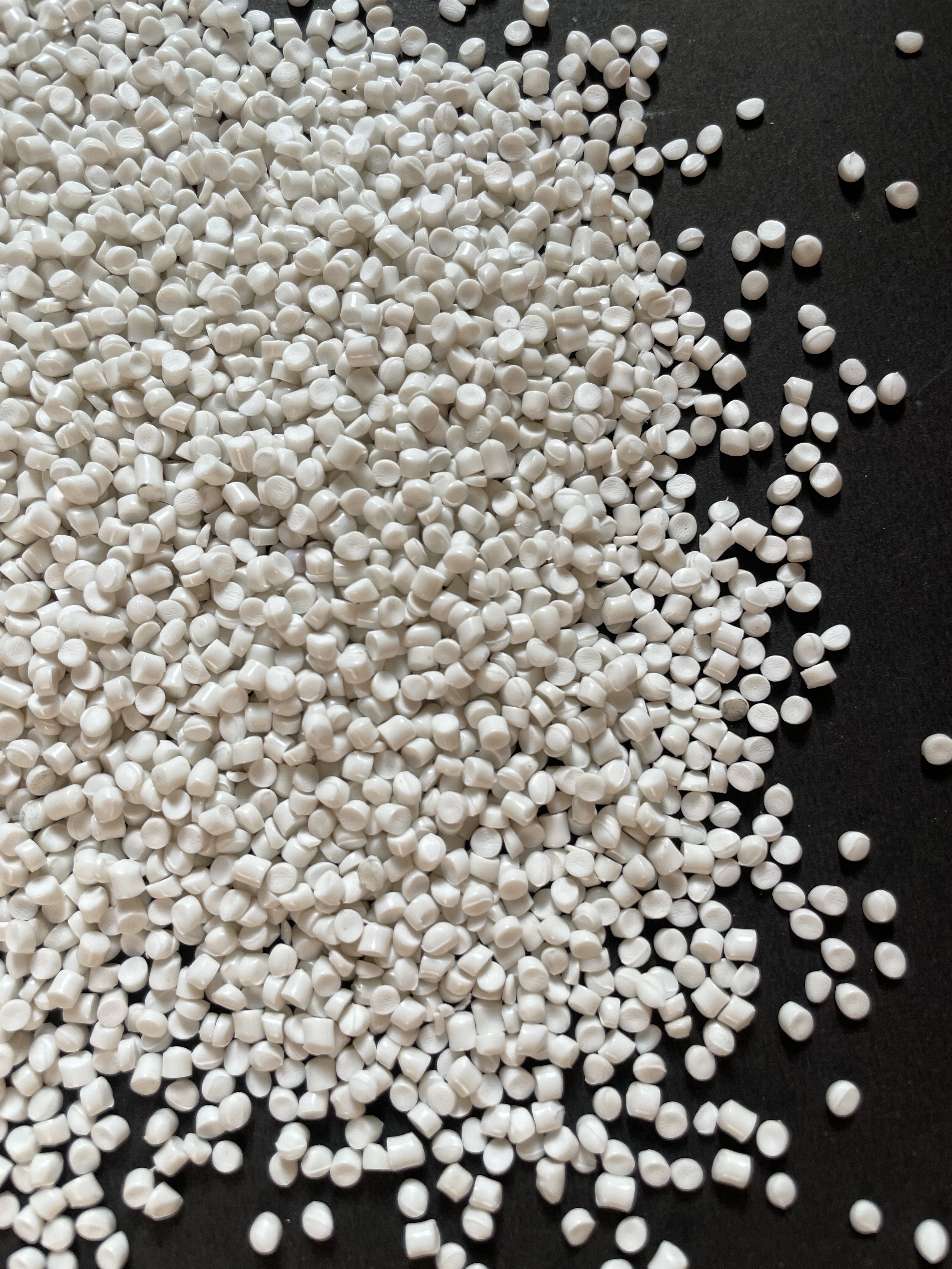 White bioplastic pellets on a dark surface